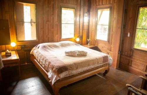 a bedroom with a bed in a room with windows at Teak House Homestay I in Ban Thung Satong