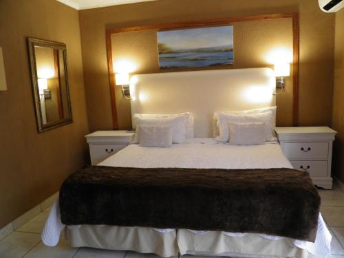 a bedroom with a large white bed with two lights at Homestay Travel Guest House in Roodepoort