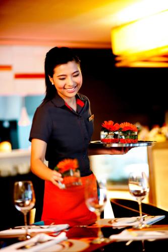 a woman standing in a kitchen with a tray of food at Sathorn Vista, Bangkok - Marriott Executive Apartments in Bangkok