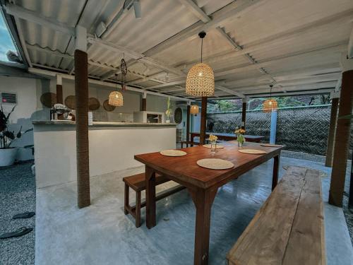 a dining room with a wooden table and a kitchen at Kickin' Surf Lodge in Weligama