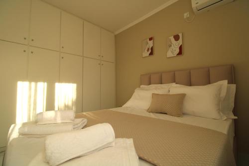 Un dormitorio con una cama con sábanas y almohadas blancas. en Serenity Oropos, en Markópoulon Oropoú