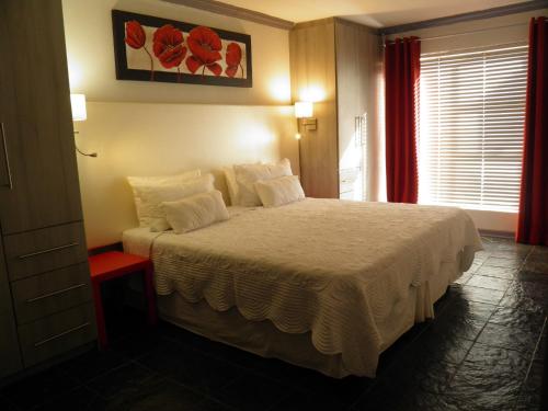 a bedroom with a bed with white sheets and a window at Homestay Travel Guest House in Roodepoort