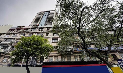Un edificio alto con árboles delante. en Hotels Heraa International, en Bombay