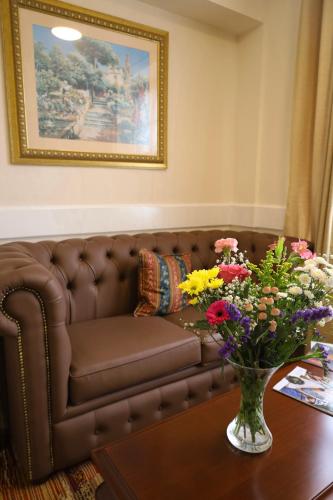 a brown couch in a living room with flowers on a table at Royal Swan, Ashley Manor - B&B in Shedfield