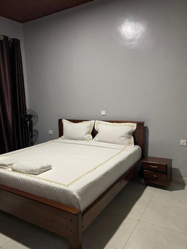 a bed with white sheets and pillows in a bedroom at RITHAN Apartment in Kigali
