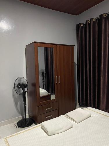 a bedroom with a bed and a dresser with a mirror at RITHAN Apartment in Kigali