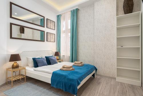 a bedroom with a bed with blue pillows and a mirror at Stylish Studio Collection Central Budapest in Budapest