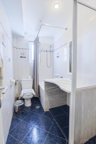 a bathroom with a toilet and a tub and a sink at Kalimera Hotel in Poros