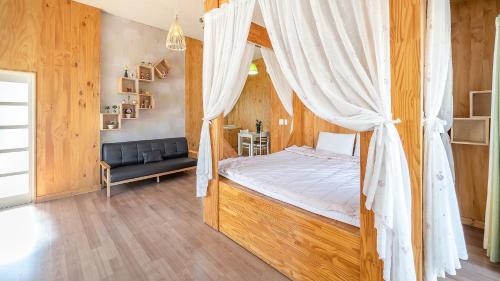 a bedroom with a canopy bed and a couch at Ganghwa Herb Pension in Incheon