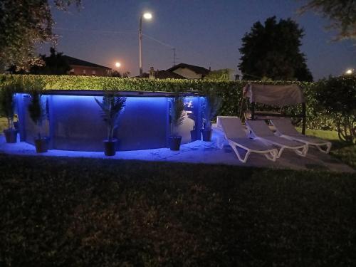 a couple of chairs sitting next to a pool at night at Villa Relax&Fly near Malpensa with Pool in Sumirago