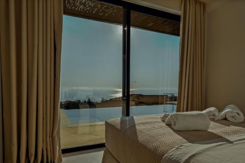 a bedroom with a bed and a large glass window at Tellion Cave Villas in Agios Nikitas