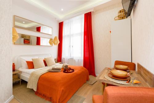 a bedroom with a bed with red curtains and a table at Stylish Studio Collection Central Budapest in Budapest