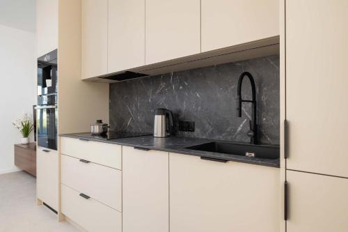 a kitchen with white cabinets and a sink at Bright Studio in Katowice with Parking, Sauna & Gym by Noclegi Renters in Katowice