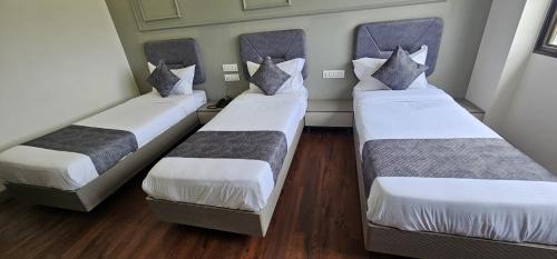 three beds in a small room with wood floors at Hotel Great View in Sangli