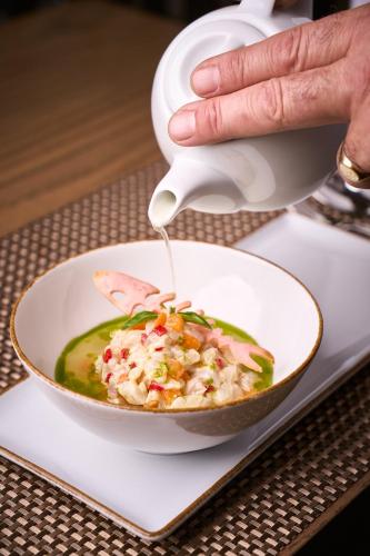 a person eating a bowl of soup with a spoon at Rocca a Mare Heraklion - Handwritten Collection in Heraklio Town