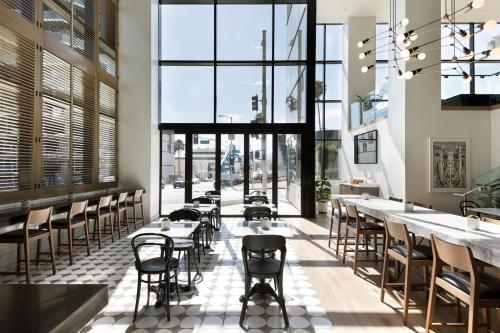 a restaurant with tables and chairs and large windows at Kimpton Everly Hotel Hollywood by IHG in Los Angeles