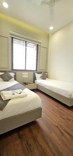 a bedroom with two beds and a window at Hotel Great View in Sangli