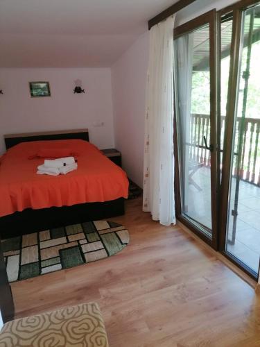 a bedroom with a red bed and a balcony at Casa Crina in Băile Herculane