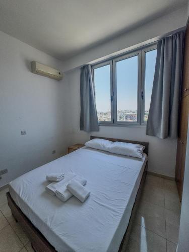 a bedroom with a bed with towels on it at Sea View City Beach Apartment in Larnaka