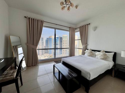a bedroom with a bed and a desk and a large window at 2 Bed Apartment in La Riviera Tower, Dubai Marina near Metro and Mall, 12-min walk to JBR Beach! in Dubai