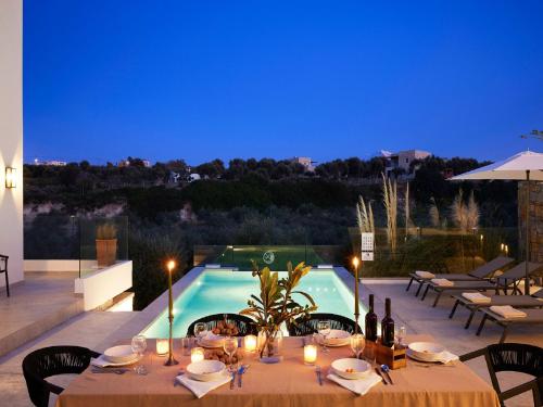 a dining table with candles and a swimming pool at Magnificent Crete Villa 4 Bedrooms Villa Ánthos Two Large Private Pools & Jacuzzi Bbq Close To The Beach Rethymno in Prínos