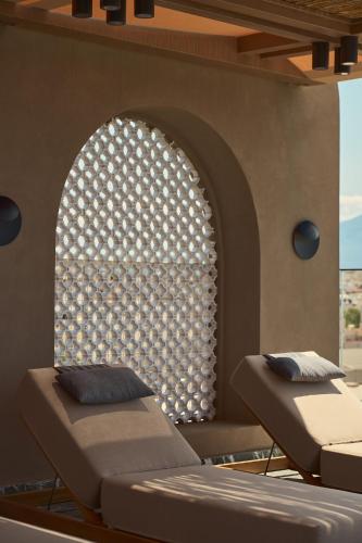 two beds in a room with an arched window at Rocca a Mare Heraklion - Handwritten Collection in Heraklio Town
