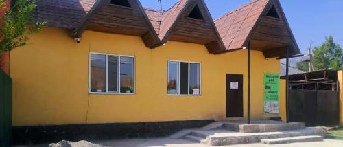 a yellow house with a brown roof at Guest house Comfort in Naryn