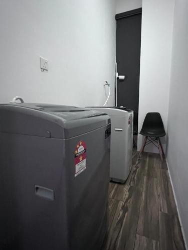 a laundry room with a washing machine and a chair at Zen 66 apartment in Kuching