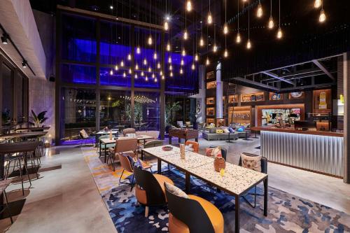 a restaurant with tables and chairs and lights at Moxy Taichung in Taichung