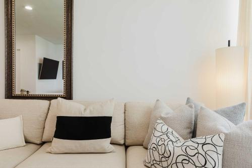 Sofá blanco con almohadas y espejo en Designer Home in Diplomat District, en Nueva York