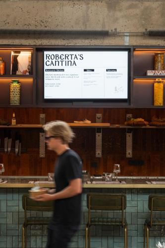 a man walking in a restaurant with a plate of food at Roberta's Society Aarhus in Aarhus