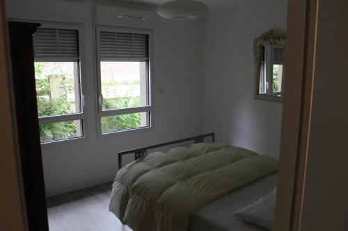 une chambre avec un lit et deux fenêtres dans l'établissement BIENVENUE EN BAIE De SOMME, à Saint-Valery-sur-Somme