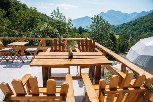 a wooden table and chairs on a deck with mountains at Ursa Camp in Gornje Lipovo