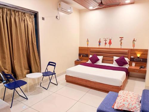 a bedroom with a bed and a couch and chairs at Passiflora Beach Resort Alibaug in Alibaug