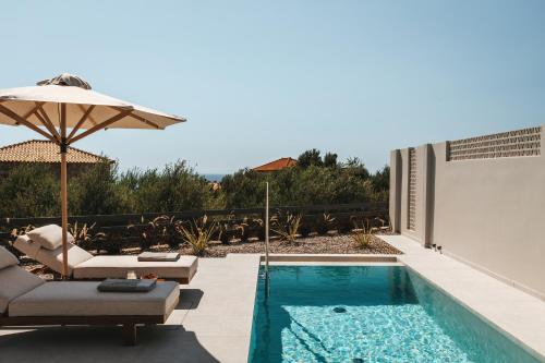 a swimming pool with chairs and an umbrella next to a house at Castor & Pollux in Kotrónion