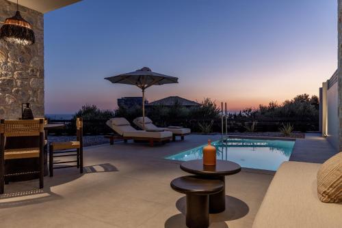 a patio with a pool with a table and chairs at Castor & Pollux in Kotrónion