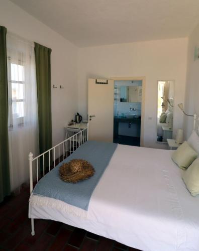 a bedroom with a large white bed and a bathroom at Moinhos das Marés in Fuzeta