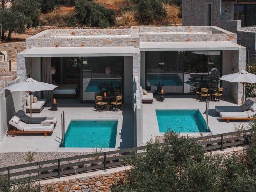 a patio with two swimming pools with chairs and umbrellas at Castor & Pollux in Kotrónion