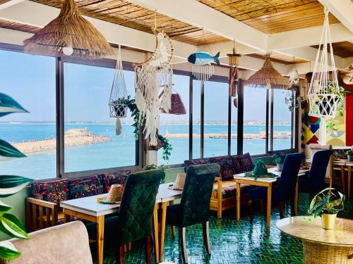 a restaurant with tables and chairs and a view of the ocean at Art riad au bord de la mer 2 in El Jadida