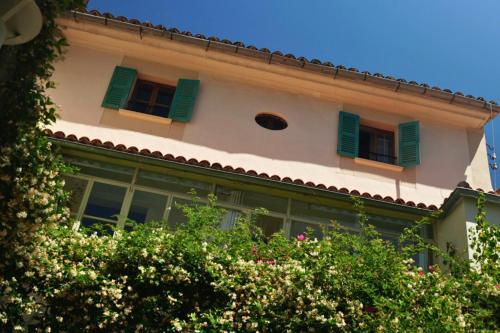 a building with green shuttered windows and some bushes at Hotel Can Abril in Sóller