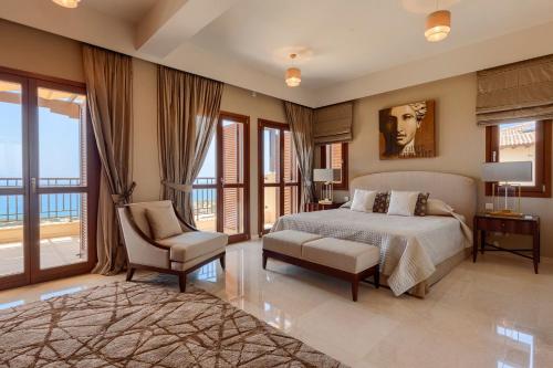 Un dormitorio con una cama y una silla y ventanas. en Aphrodite Hills Mythos Collection Villa Iris Private Pool Sea View 5 Bedrooms Paphos, en Paphos