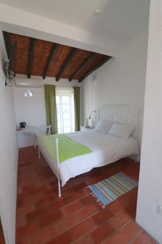 a bedroom with a white bed and a window at Moinhos das Marés in Fuzeta