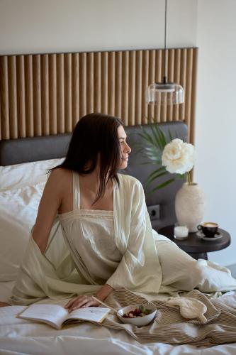 a woman sitting on a bed reading a book at Rocca a Mare Heraklion - Handwritten Collection in Heraklio Town