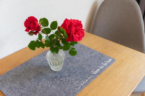 a vase with red roses sitting on a table at Biolandhaus Seethaler in Vorderthiersee