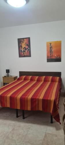 a bed with a striped comforter in a room at casa al mare kalispera in Marina di Mancaversa