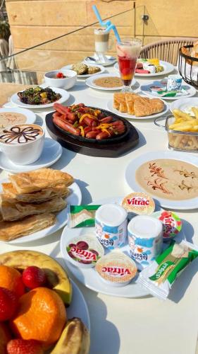 a table topped with plates of food and fruit at Cleo Patra Pyramids Tower Inn in Banī Ghālib