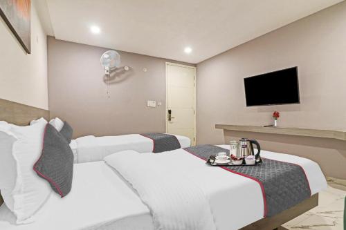 a hotel room with two beds and a flat screen tv at Super Hotel O THE FERN SUITES in Hyderabad