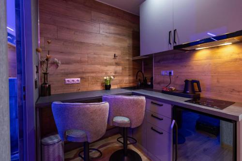 a kitchen with two bar stools and a counter at Royal Apartments Gold-Silver Kecskemet in Kecskemét