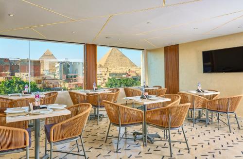 a restaurant with tables and chairs and a view of the pyramids at Cleo Patra Pyramids Tower Inn in Banī Ghālib