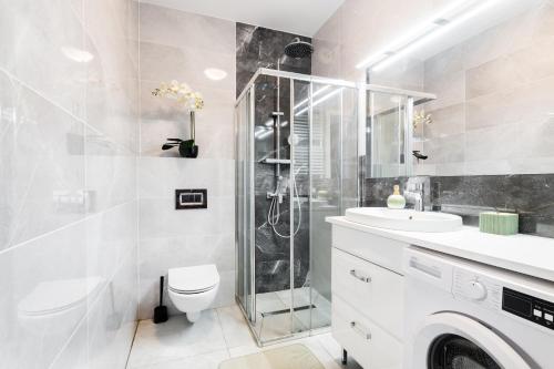 a bathroom with a toilet sink and a shower at Business Suites Arkadia by VAYA STAYS in Warsaw